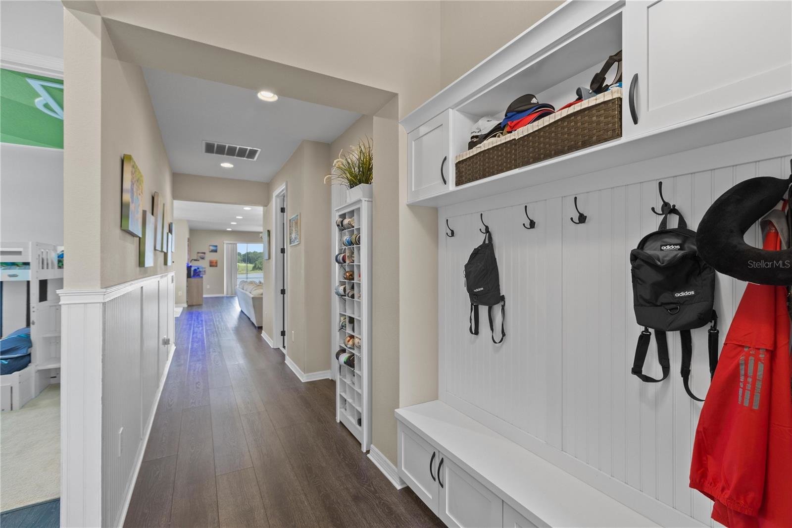 entryway with white walls and hooks to hang bags